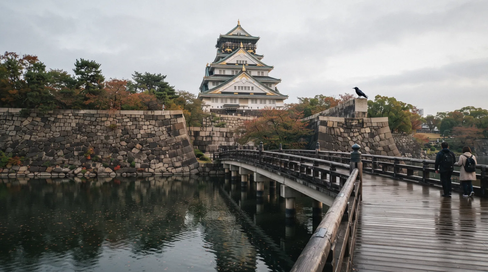 The gold-trimmed keep of Osaka Castle above its Tokugawa-era stone wall and inner moat in morning light, Osaka Japan