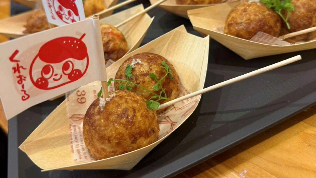 Takoyaki turning on a griddle at a Dotonbori stall on a six-shop takoyaki tasting tour, Osaka Japan