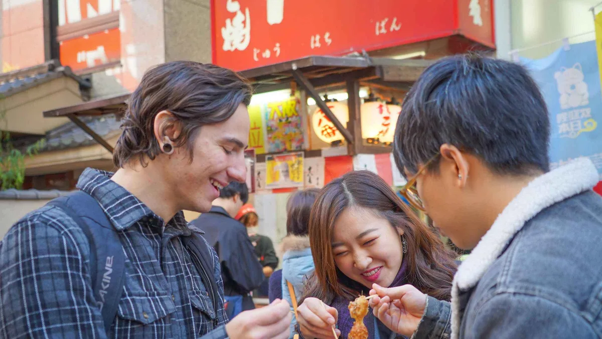 Guest cooking okonomiyaki on a hot griddle on a Dotonbori and Shinsekai food tour, Osaka Japan