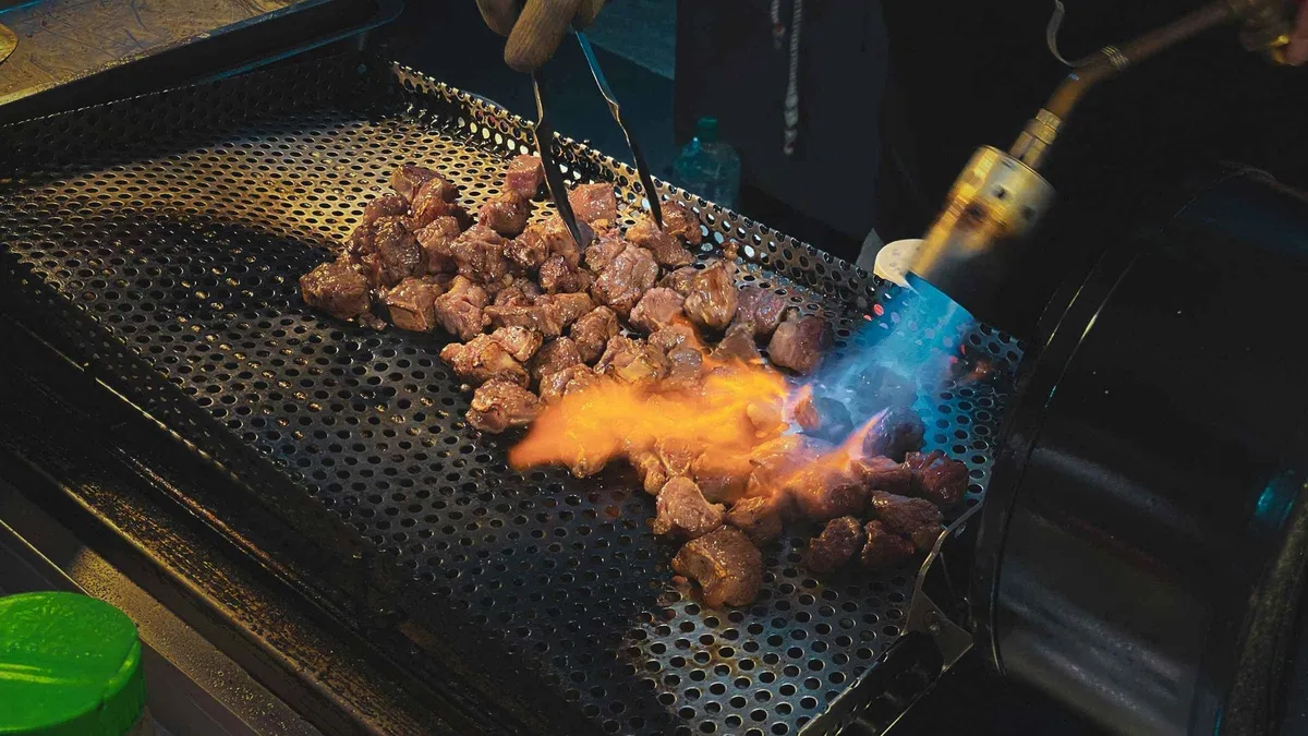 Wagyu skewers grilling at a Kuromon Market stall on a wagyu and street food tour, Osaka Japan